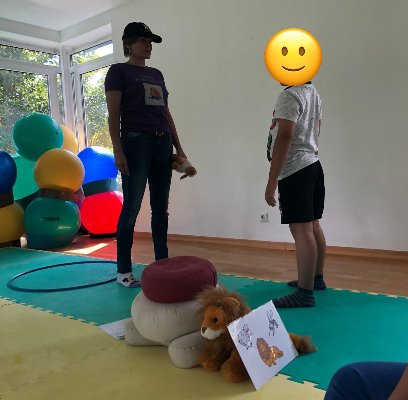 Einzeltraining in einem hellen Raum mit Gymnastikbällen: Nathalie Barth im Gespräch mit einem Kind, dessen Gesicht verdeckt ist